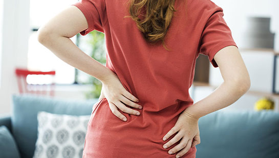 Woman holding lower back in pain before visiting Lake Worth chiropractor